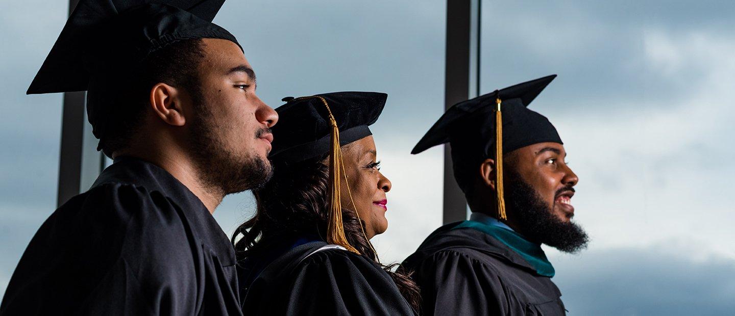 Three African American students in their graduation caps and gowns.