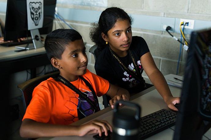 一个男孩和一个女孩看着电脑显示器